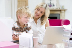 Woman and young boy in home office with laptop smiling